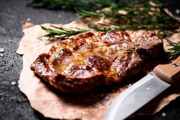 Grilled pork steak on paper with rosemary. 