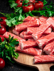 Fresh crab meat on a cutting board with parsley and tomatoes. 