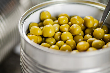 Open tin can with canned green peas with a spoon. 