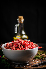 Minced meat in a bowl on a cutting board with sprigs of thyme. 