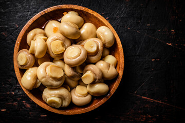 Homemade pickled mushrooms in a wooden bowl. 