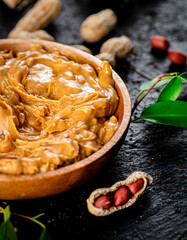 Peanut butter in a wooden plate on the table. 