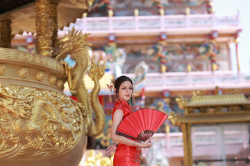 Portrait Chinese girl or Asia woman with red qipao hold handmade fan posing on Chinese new year