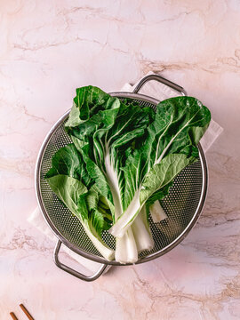 Cut bok choy on a pink marble surface.