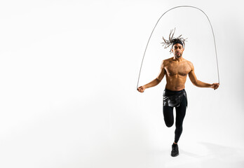 Young athletic and determined Black man skipping jump rope on white background in an indoor studio - Powered by Adobe