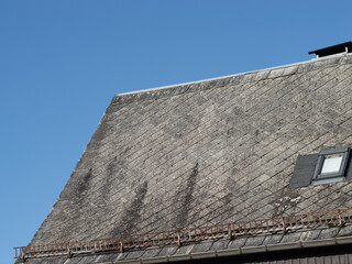 Hazardous asbestos sheets as roof tiles on a residential building. Weathered exterior of a house. The material was used in the German Democratic Republic because it was cheap and fire resistant.