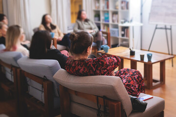 Female participants audience at the symposyum meeting,  attendees in conference room hall listens to lecturer, group of women on a congress together listen to speaker on a stage at master-class