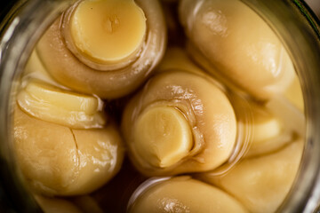 Open glass jar with pickled mushrooms. 