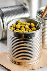 Open tin can with canned green peas with a spoon. 