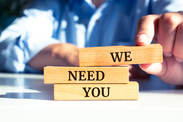 Close up on businessman holding a wooden block with "We Need You" message
