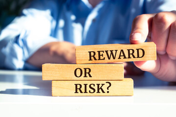 Close up on businessman holding a wooden block with "Reward or Risk?" message