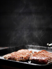 Cooking grilled steak in a frying pan with hot steam. 