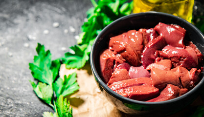 Sliced raw liver in a bowl with parsley.
