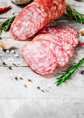 Pieces of salami sausage with spices, rosemary and chili peppers. 