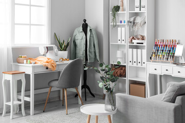 Interior of light atelier with tailor's workplace, mannequin and shelving unit