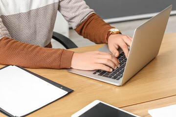 Young businessman working with laptop at desk in office, closeup