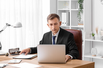 Young businessman working with laptop at desk in office