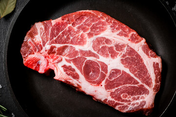 Raw pork steak in a frying pan. 