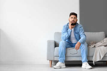 Stressed young man sitting on sofa at home