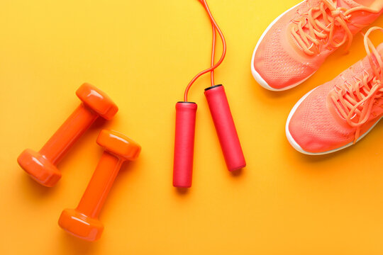 Skipping rope, dumbbells and sneakers on yellow background © Pixel-Shot