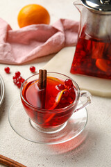 Glass cup of fruit tea with red currant and cinnamon on light background, closeup