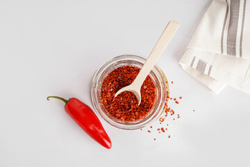 Glass with chipotle chili flakes on light background