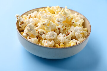 Bowl full of tasty popcorn on color background