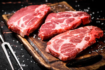 Raw pork steak on a wooden cutting board. 