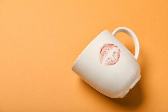 Cup with lipstick kiss mark on orange background