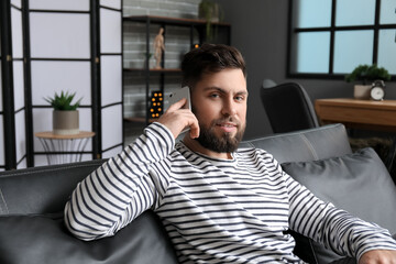 Young bearded man talking by mobile phone in office