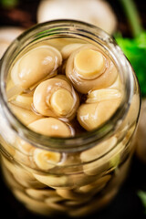Pickled mushrooms in a glass jar on the table. 