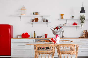 Interior of kitchen decorated for Valentine's Day with flowers, dining table and counters