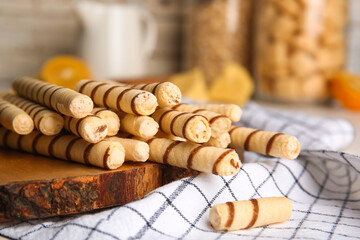 Cutting board with tasty wafer rolls and kitchen towel on table, closeup