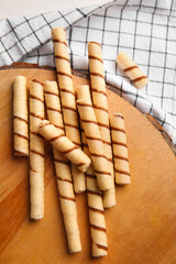 Cutting board with tasty wafer rolls and kitchen towel on table