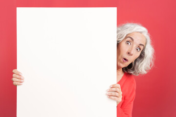 Surprised mature woman holding a blank board