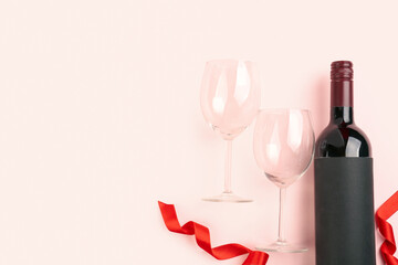 Bottle of wine, ribbon and glasses on pink background. Valentine's Day Celebration