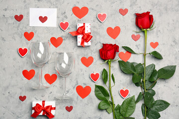 Paper hearts, rose flowers, gift boxes, envelope and wine glasses on grey table. Valentine's Day celebration