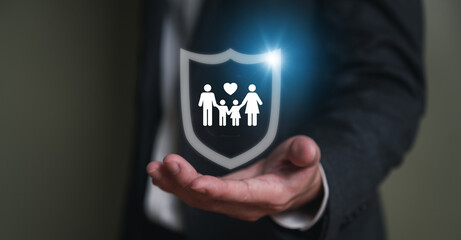 Insurance agent with formal suit using hand to protect customer family from falling wood brick. With icon of the family with shield to prevent the risk and accident. Risk management with insurance.