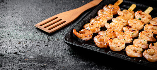 Shrimp on skewers are grilled in a grill pan. 