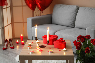 Burning candles and gifts for Valentine's Day on table in living room