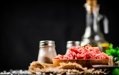 Minced meat in a plate on burlap with spices. 