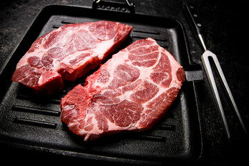Raw pork steak in a frying pan. 