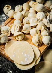 Fototapeta na wymiar Raw dumplings with pieces of dough on a wooden cutting board. 