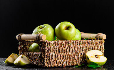 A basket full of green apples with leaves. 