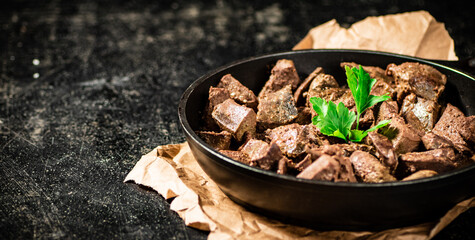 Liver in a frying pan on paper with a sprig of parsley. 