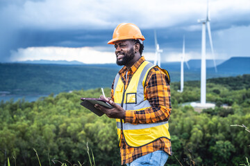 Obraz premium Portrait of engineer African American man working with laptop in wind turbine farm.