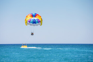  flying on a parachute behind a boat on a summer holiday by the sea in the resort of Turkey. Parasailing, active sport in beautiful summer day.
