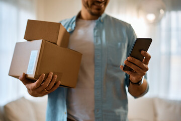 Close up of man with delivered packages texting on mobile phone.