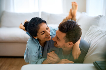Fototapeta premium Happy couple in love talking while lying down on sofa.