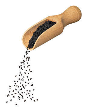black cumin seeds falling from wooden scoop isolated on white